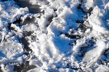 Melting ice floating on the river on a sunny spring day. Cracked ice texture.