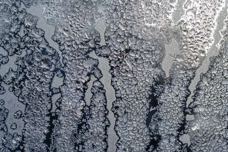 The texture of the glass covered with frost in winter in cold weather. Abstract natural background.