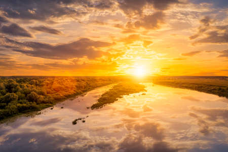 Aerial view to sunset on the river at summer evening with clouds and willow trees. Water reflection...