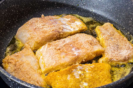 Breaded white fish steaks, fried in a pan with vegetable oil.の写真素材