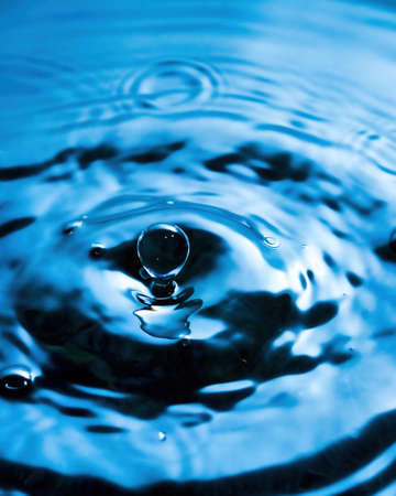 A drop of water and splashes with blurry waves on it.