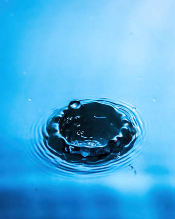 A drop of water and splashes with blurry waves on it.
