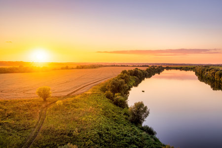 A sunset or sunrise scene over a lake or river with skies reflecting in the water on a summer...