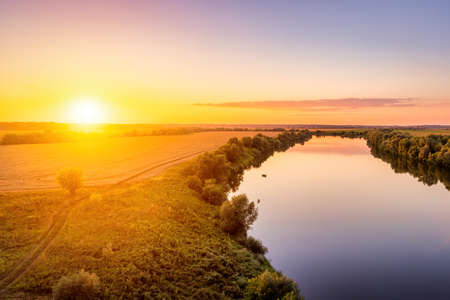 A sunset or sunrise scene over a lake or river with skies reflecting in the water on a summer...