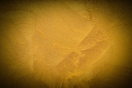 Texture of golden decorative plaster or concrete with vignette. Abstract grunge background for design.の写真素材