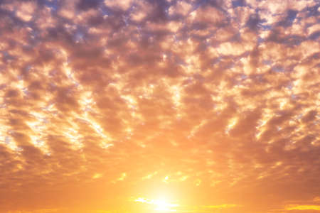 Dramatic cloudy sky illuminated by the rays at sunset or sunrise.