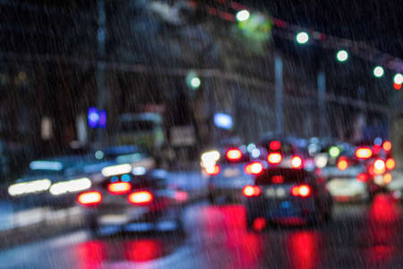 Blurry lights of moving cars and lanterns reflecting on the wet asphalt in the night city in rain. Rainy bad weather concept.の写真素材