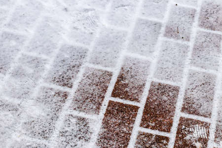 The texture of the cobblestone path covered with the first snow in winter. Abstract winter background.の写真素材