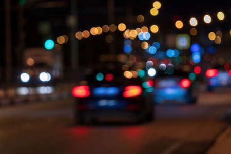Blurry lights of moving cars and lanterns reflecting on the wet asphalt in the night city. Bad weather concept.の写真素材