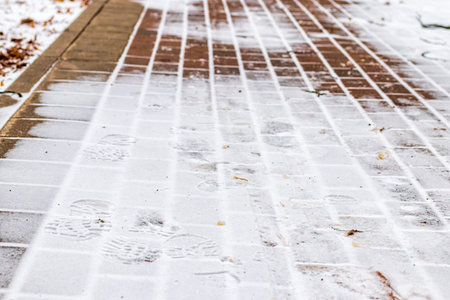 Paving paths in the park, covered with the first snow in winter. Winter weather or first snow concept.の写真素材