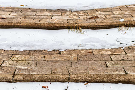 Paving paths in the park, covered with the first snow in winter. Winter weather or first snow concept.の写真素材