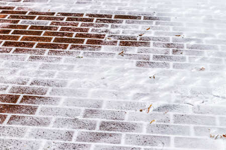 The texture of the cobblestone path covered with the first snow in winter. Abstract winter background.の写真素材