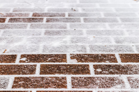 The texture of the cobblestone path covered with the first snow in winter. Abstract winter background.の写真素材