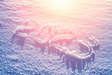 The number 2023 written in the snow illuminated by sunlight. New year and christmas concept.の写真素材