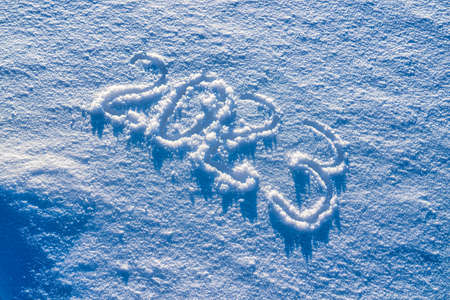 The number 2023 written in the snow illuminated by sunlight. New year and christmas concept.の写真素材