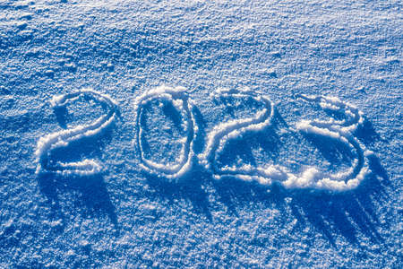 The number 2023 written in the snow illuminated by sunlight. New year and christmas concept.の写真素材
