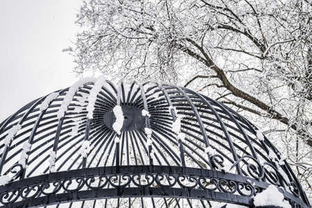 Black metal grate covered with snow in winter. Snowfall and winter weather concept.
