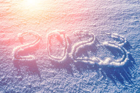 The number 2023 written in the snow illuminated by sunlight. New year and christmas concept.の写真素材