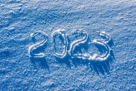 The number 2023 written in the snow illuminated by sunlight. New year and christmas concept.