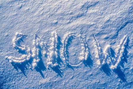 The word "snow" written on the snow in sunny weather. Winter and cold weather concept.の写真素材