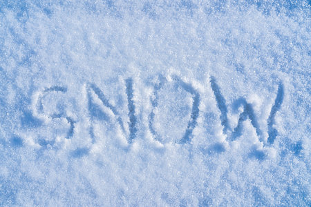 The word "snow" written on the snow in sunny weather. Winter and cold weather concept.の写真素材