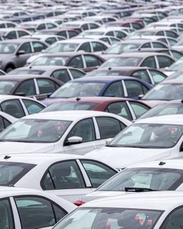 Rows of a new cars parked in a distribution center on a car factory parking.