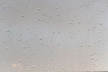 Raindrops on a window with a sunset sky in the background. Clear weather after the rain.