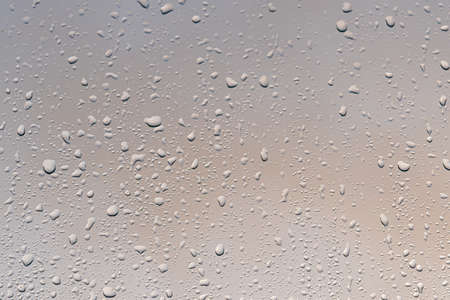 Raindrops on a window with a sunset sky in the background. Clear weather after the rain.の写真素材