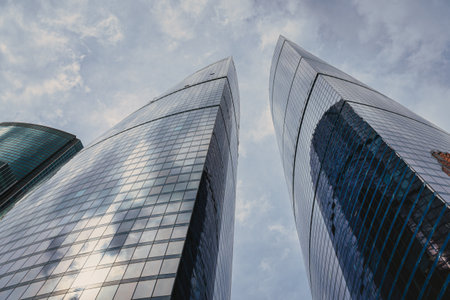 RUSSIA, MOSCOW - JULY 17, 2022: Low angle view of Moscow-City skyscrapers. New business and finance district in Moscow downtown. Tops of modern corporate buildings against the cloudy sky.のeditorial素材