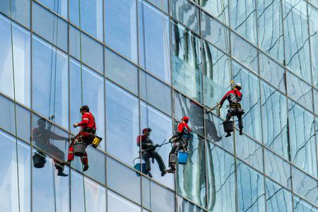 Group of industrial climbers cleaning windows on the facade of an office building at a height.のeditorial素材