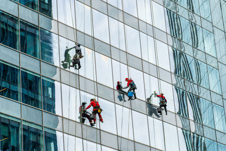 Group of industrial climbers cleaning windows on the facade of an office building at a height.のeditorial素材