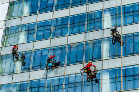 Group of industrial climbers cleaning windows on the facade of an office building at a height.のeditorial素材