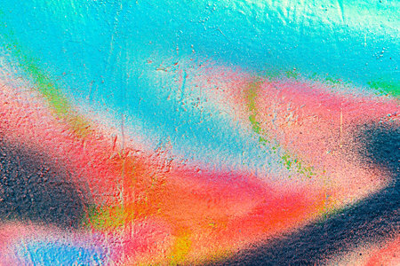 A fragment of colorful graffiti painted on a wall. Abstract urban background for design. spray...