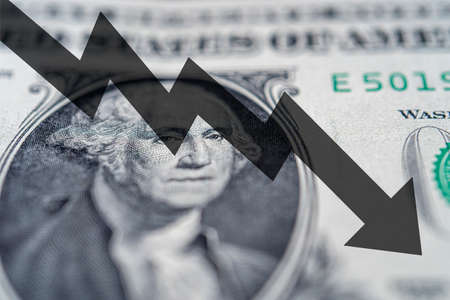 Arrow down on the background of dollar bill. The concept of inflation, depreciation of the dollar, wealth or the US economy.の写真素材