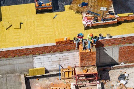 RUSSIA, KALUGA - AUGUST 15, 2022 : A group of workers assembling the framework of a building from...