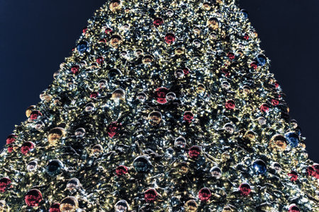 Christmas balls and glowing garlands on an artificial spruce. Xmas abstract background.