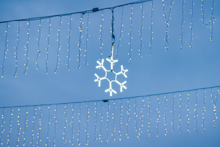 New Year or Christmas festive snowflake and garlands hanging in rows on twilight.