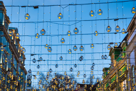 Festive hanging garlands with glowing light bulbs against the background of the night sky. Holiday decorations.の写真素材