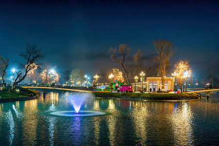 TASHKENT, UZBEKISTAN - DECEMBER 20, 2022: "Magic City" amusement park on a late evening reflected in a water.のeditorial素材