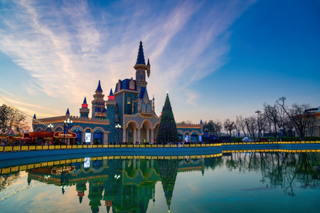 TASHKENT, UZBEKISTAN - DECEMBER 20, 2022: "Magic City" amusement park on a late evening reflected in a water.のeditorial素材