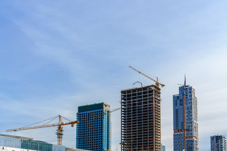 A crane building a modern skyscraper against a blue sky. construction site.の写真素材