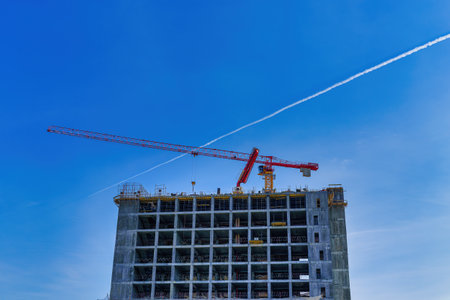 A crane building a modern skyscraper against a blue sky. construction site.の写真素材