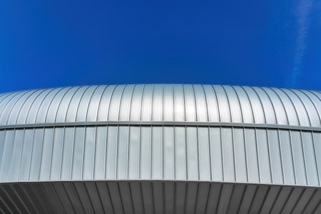 A fragment of a modern building covered with metal aluminum panels against the blue sky.の写真素材