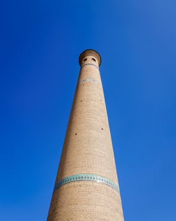 The minaret of a brick mosque against a blue cloudless sky.の写真素材