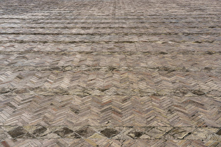 The texture of a stone old monotonous pavement with a perspective.