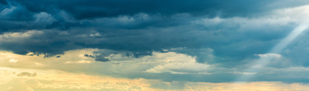 Sunbeams breaking through dramatic cumulus clouds. Weather change from stormy to sunny. hope or...