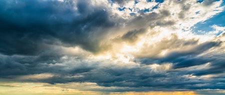 Sunbeams breaking through dramatic cumulus clouds. Weather change from stormy to sunny. hope or religion concept.の写真素材