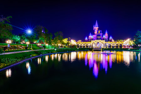TASHKENT, UZBEKISTAN - APRIL 20, 2023: Magic City amusement park on a late evening reflected in a water.のeditorial素材