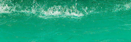 Turquoise flow of falling water and splashes from it, illuminated by sunlight. nature abstract...