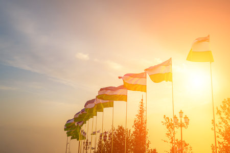 Flags of Uzbekistan waving on a sunset or sunrise dramatic cloudy sky background.の写真素材